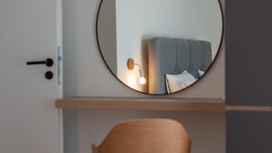 A modern room with a round mirror on the wall, a wooden chair, and a bed with a headboard. - Villa Eight by A (Okrug)