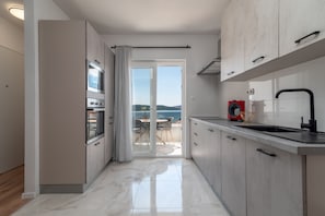 Enjoy a spacious kitchen with sleek cabinetry, stainless steel oven, and a large window opening to a balcony with a scenic view.