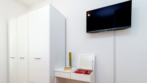 A white room with a desk, a red stool, a mirror, and a TV mounted on the wall. - Villa Eight by A (Okrug)