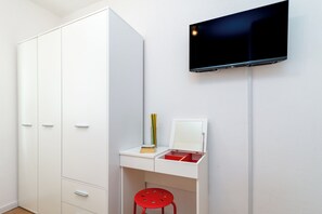 A white room with a desk, a red stool, a mirror, and a TV mounted on the wall. - Villa Eight by A (Okrug)