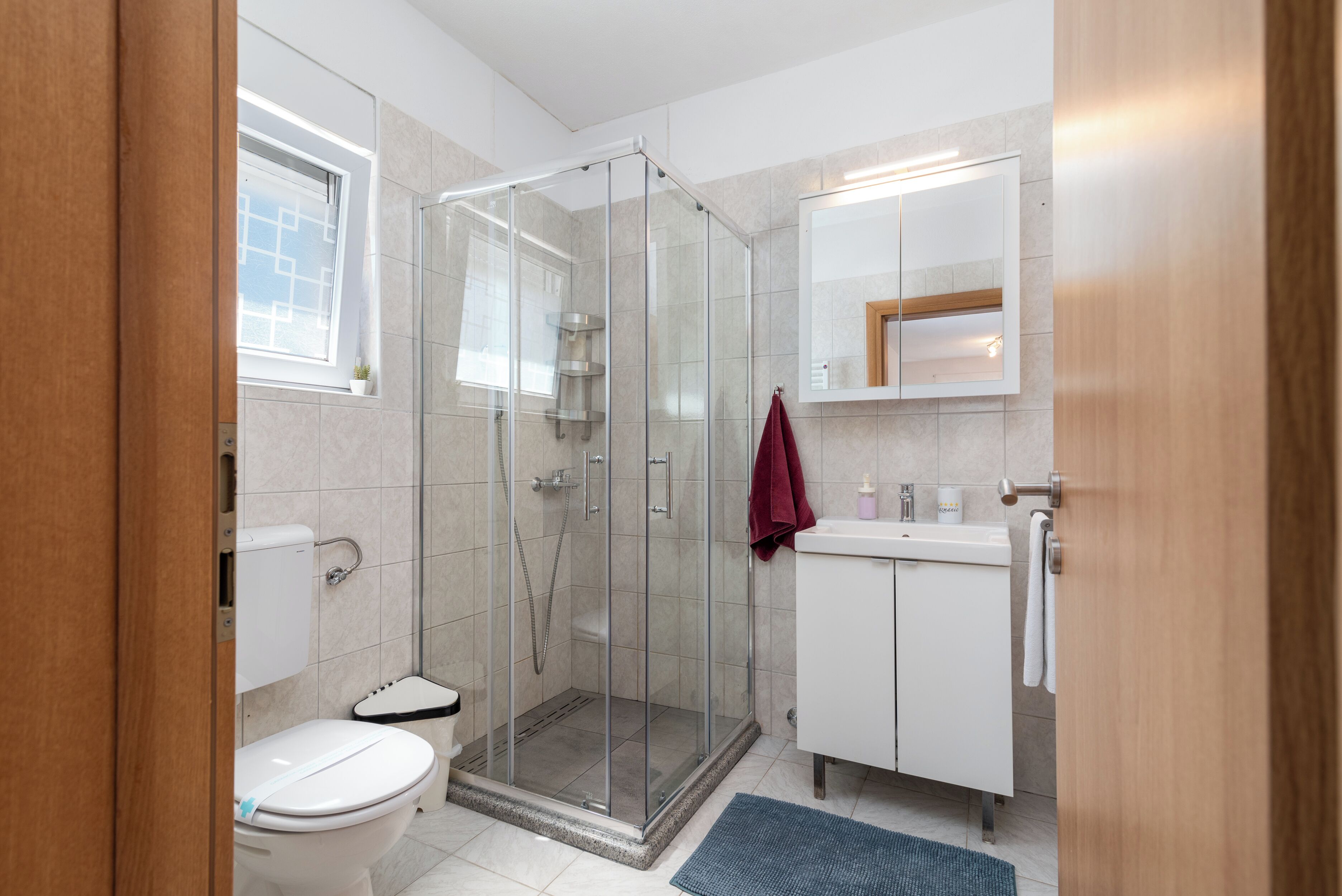 Ein modernes Badezimmer mit einer Duschkabine, einer Toilette, einem Waschbecken und einem Spiegel darüber.