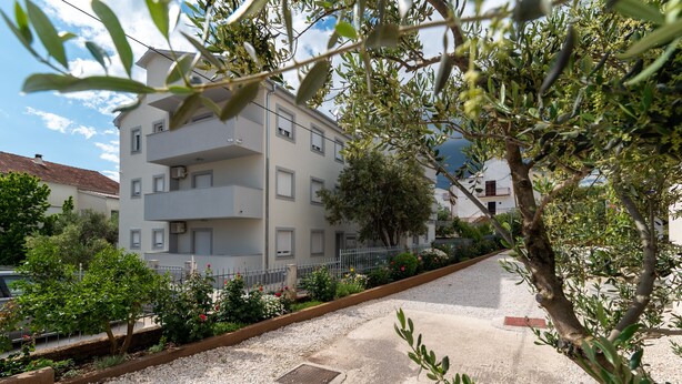 A multi-story building with balconies, surrounded by gravel pathways and greenery. - Villa Eight by A (Okrug)
