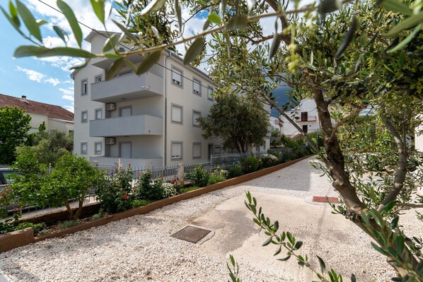 A multi-story building with balconies, surrounded by gravel pathways and greenery. - Villa Eight by A (Okrug)