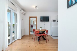Una cocina moderna con una televisión de pantalla plana, un refrigerador y un microondas.