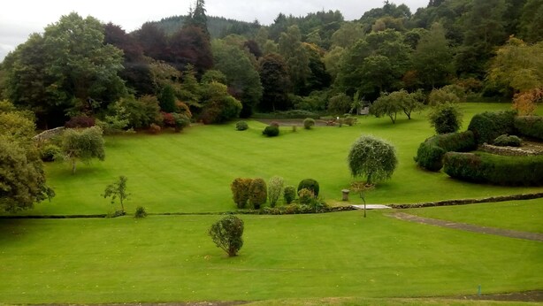 A well-maintained lawn with neatly trimmed hedges and a variety of trees. - Elibank House B&B (Walkerburn)