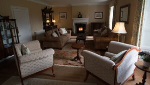 A traditional living room with a fireplace, two sofas, a coffee table, and a lamp. - Elibank House B&B (Walkerburn)