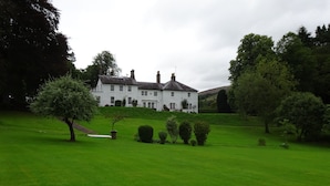 A large, white, two-story house with a symmetrical facade, surrounded by a well-maintained lawn and several trees. - Elibank House B&B (Walkerburn)