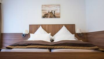 Una cama bien hecha con cabecera de madera, dos lámparas de noche y un cuadro enmarcado sobre ella.
