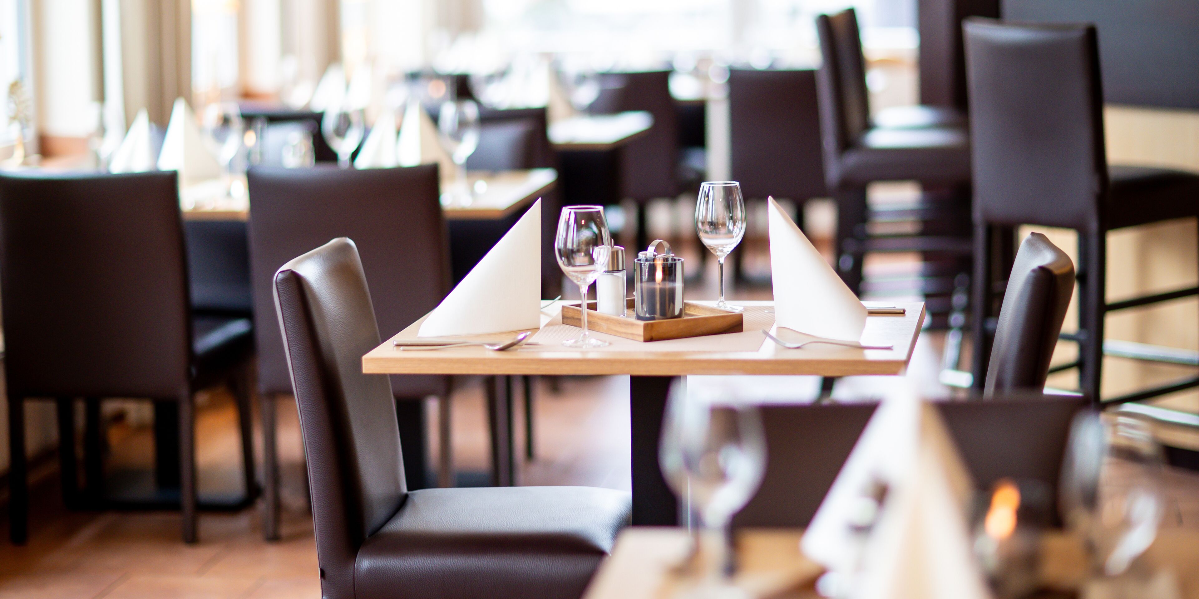 Ein Restaurant mit gedeckten Tischen, Stühlen und Weingläsern.
