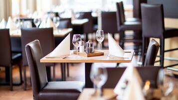 Ein Restaurant mit gedeckten Tischen, Stühlen und Weingläsern.