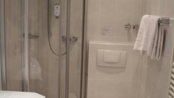 A bathroom with a glass-enclosed shower, a toilet, a sink, and a towel rack.