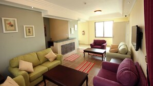 Una sala de estar con un sofá verde, un sofá morado, una mesa de centro y una chimenea.