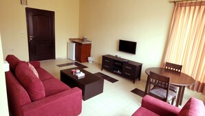 Una sala de estar con un sofá, una mesa de centro, televisor y un pequeño comedor con una mesa y sillas.