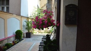 A narrow outdoor corridor with a potted plant, a bench, and a mailbox. - Bon Bon Hotel (Sofia)