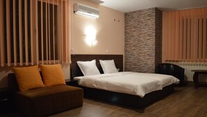 A hotel room with a bed, a sofa, a desk, and a stone accent wall. - Bon Bon Hotel (Sofia)