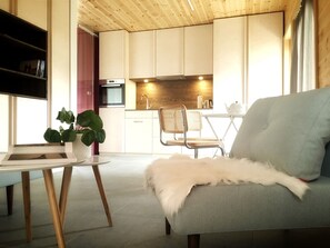 Una sala de estar moderna con un sofá gris, un plaid blanco y mullido, una mesa de centro de madera y una silla de mimbre.