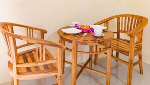 A wooden table with two chairs, a white plate, a cup, and a flower arrangement. - Alam Pangkung Ubud (Ubud)