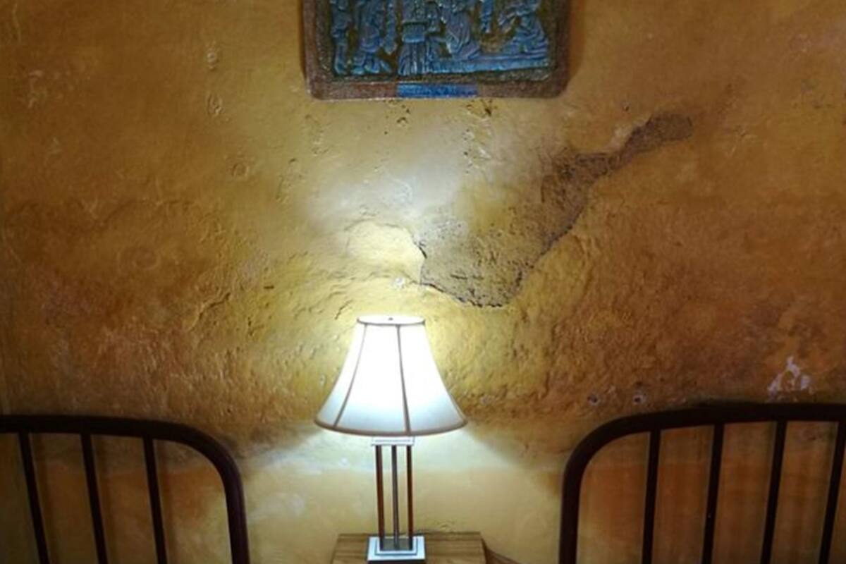 A small room with two beds, a nightstand with a lamp, and a wall with a decorative plaque.