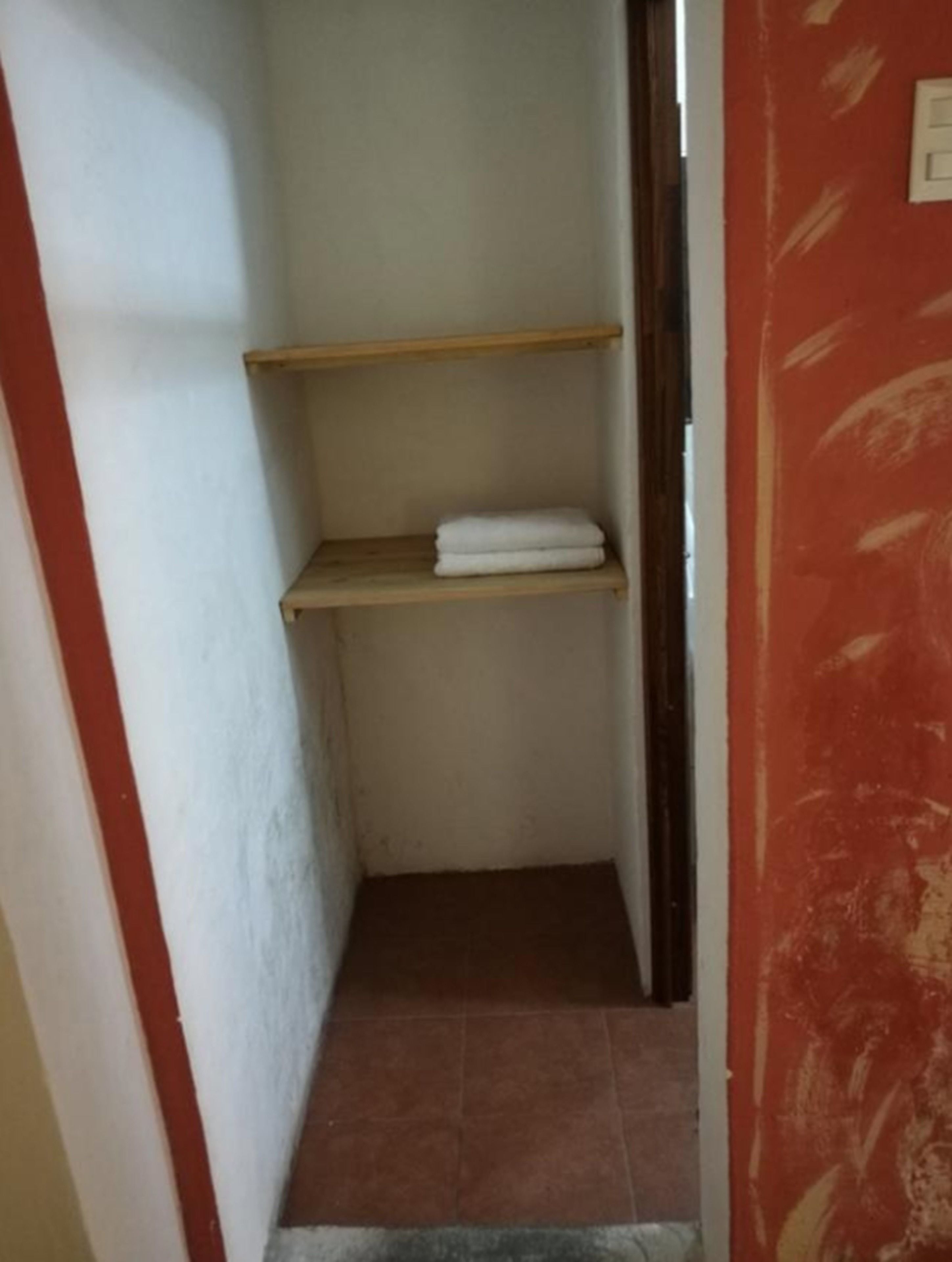 Un couloir étroit avec une étagère en bois et un sol carrelé.