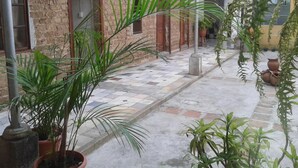 A courtyard with a stone wall, potted plants, and a tiled floor.