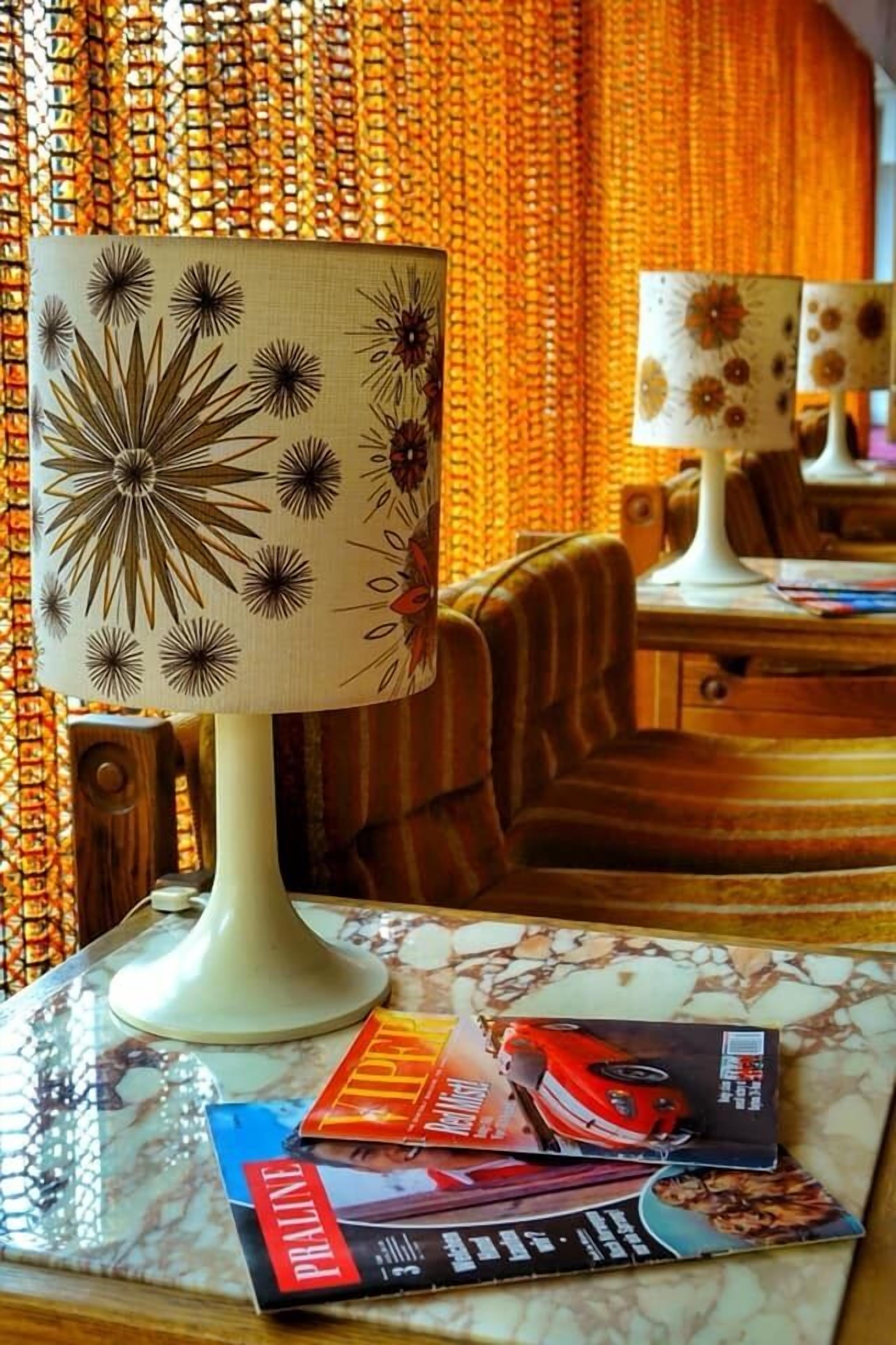 Ein Zimmer mit einer gemusterten Lampe, einem Tisch mit Zeitschriften und einem Stuhl.