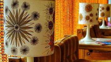Ein Zimmer mit einer gemusterten Lampe, einem Tisch mit Zeitschriften und einem Stuhl.