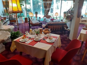 A dining area with a table set for breakfast, including plates, cups, and a fruit bowl.
