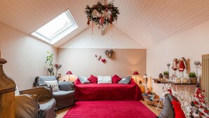 A cozy room with a red sofa, a wooden floor, a skylight, and holiday decorations. - La Rose Tremiere (Wintzenheim-Kochersberg)