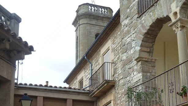 A narrow street with stone buildings, a central archway, and a tower.