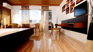A modern hotel room with a large bed, wooden flooring, a TV mounted on the wall, and a balcony with a view. - Hotel Restaurant Es Lämmche (Breuberg)