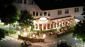 A two-story building with a restaurant on the ground floor. There are outdoor seating areas with tables and chairs. - Hotel Restaurant Es Lämmche (Breuberg)