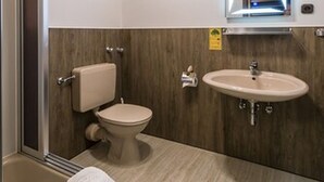 A bathroom with a wooden ceiling, a toilet, a sink, and a mirror. - Hotel Restaurant Es Lämmche (Breuberg)