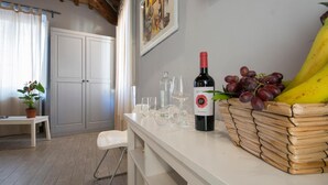 A kitchen with a white countertop, a wine bottle, glasses, a fruit basket, and a potted plant. - B&B Le Casine di Firenze (Florence)