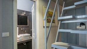 A bathroom with a sink, mirror, and towel rack. There is a painting on the wall and a ladder leading to a storage area. - B&B Le Casine di Firenze (Florence)