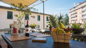 A table set outdoors with a bottle of wine, glasses, a lantern, and a basket of fruit. - B&B Le Casine di Firenze (Florence)