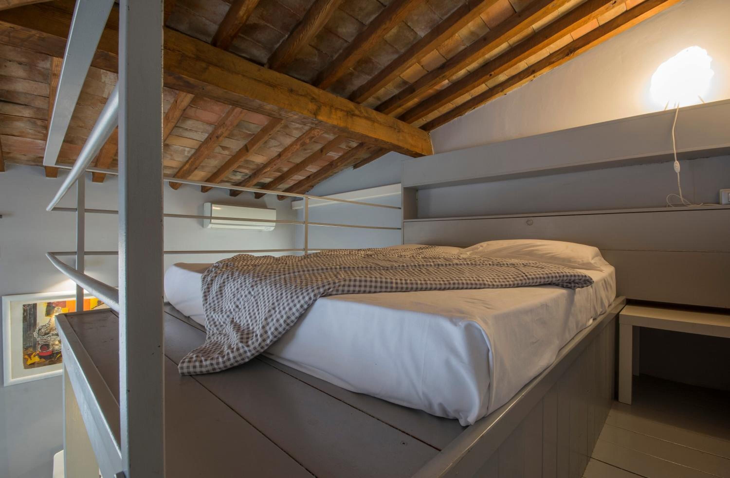 A bunk bed in a room with a wooden ceiling and a white wall.