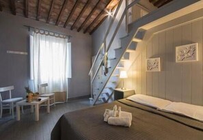 Een hotelkamer met een bed, een bureau, een stoel, een trap en kunstwerken aan de wanden.