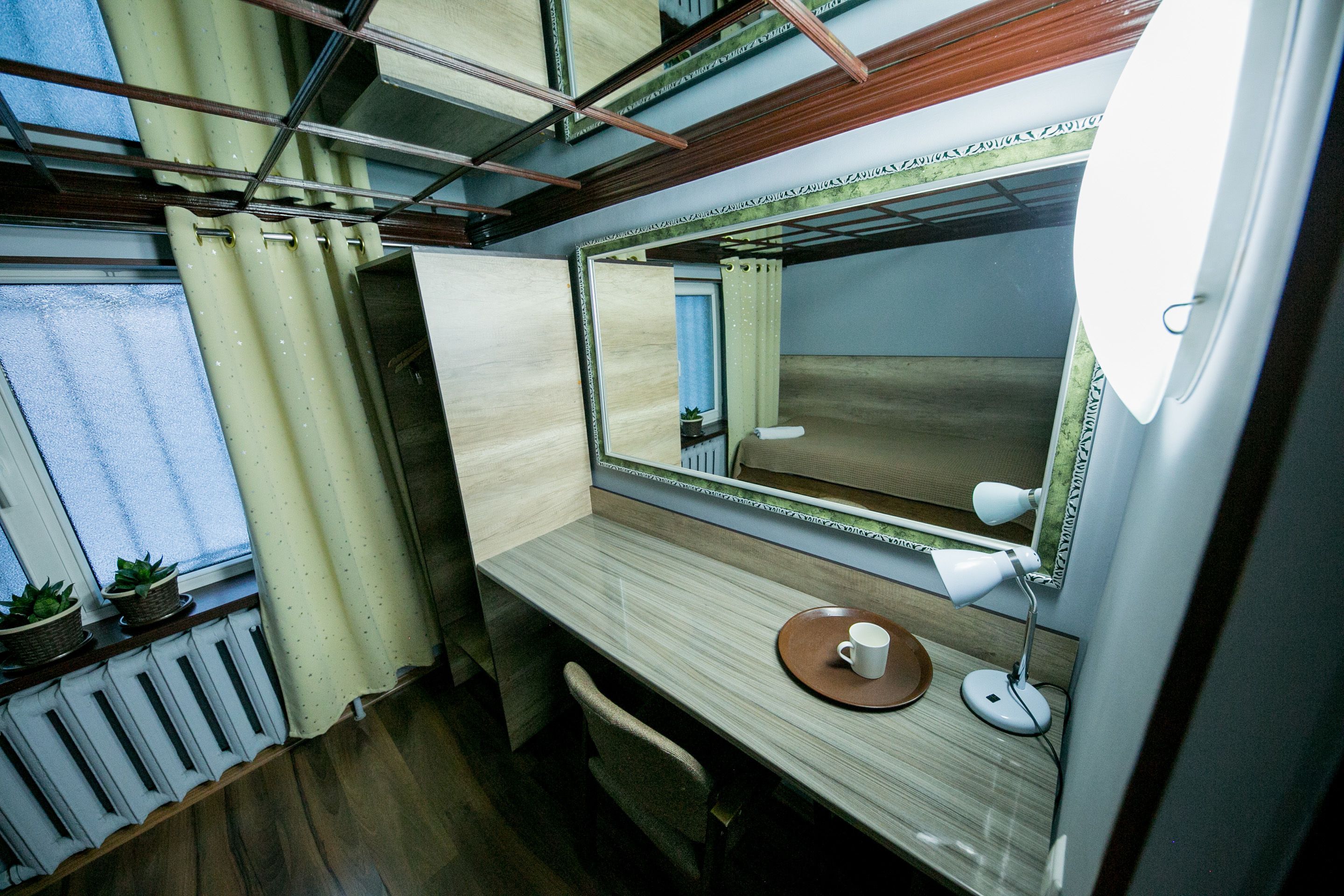 A compact, well-lit bathroom with a wooden vanity, a mirror, a small table with a cup, and a potted plant.