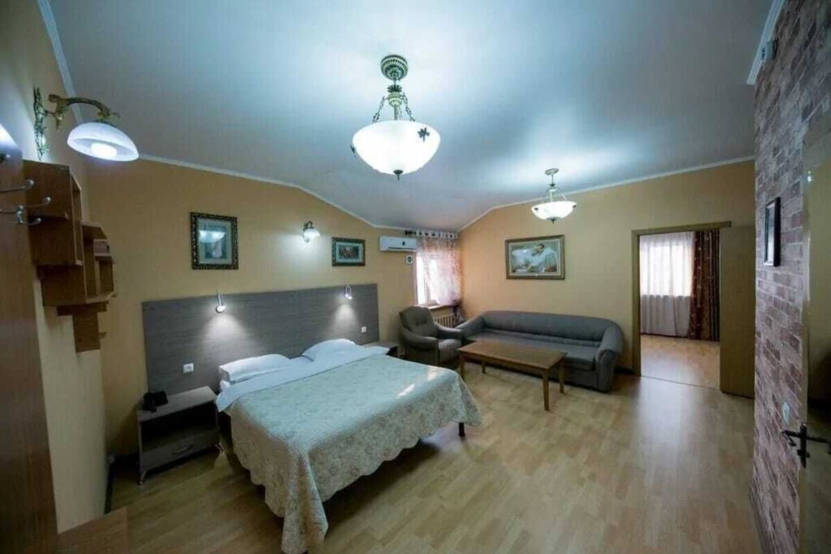 Un dormitorio con cama, sofá, sillón, mesa y lámpara de techo.