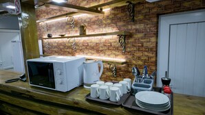 A kitchen area with a microwave, coffee maker, and various mugs and dishes on a tray.