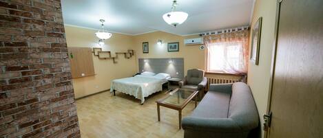 Una habitación con una pared de acento de ladrillo, una cama, un sofá, una mesa de centro de vidrio y una lámpara en el techo.