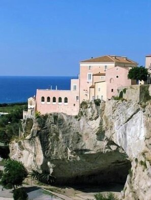 A coastal building with multiple levels, arched windows, and a view of the sea. - La Casa di Chiaretta (Falerna)