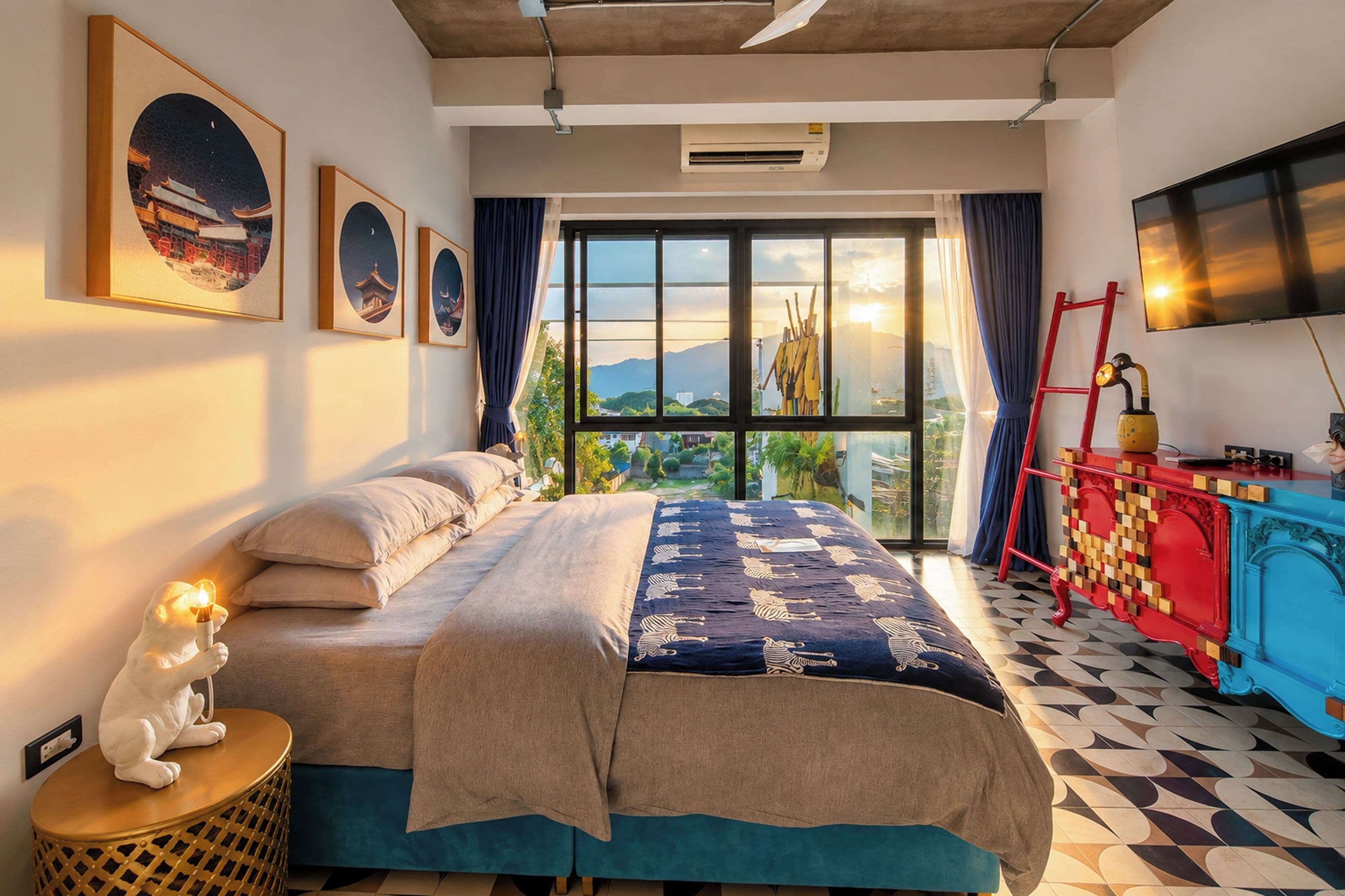 Habitació d'hotel amb llit, televisió, finestra amb vista i obra d'art a la paret.