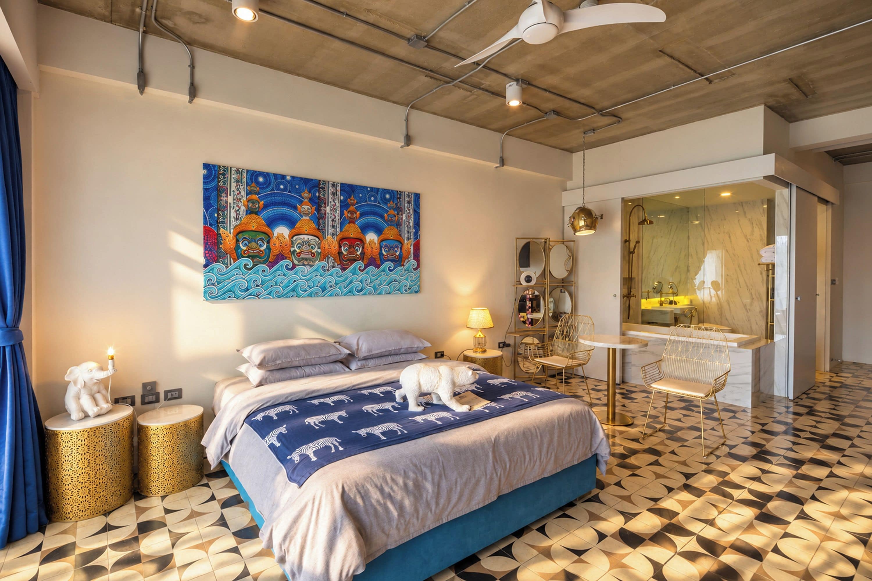 A modern bedroom with a large bed, a painting, a bathroom with a mirror, and a patterned floor.