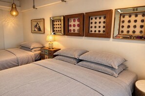 A hotel room with two beds, a nightstand, a lamp, and wall-mounted artwork. - River Art Hotel (Chiang Mai)
