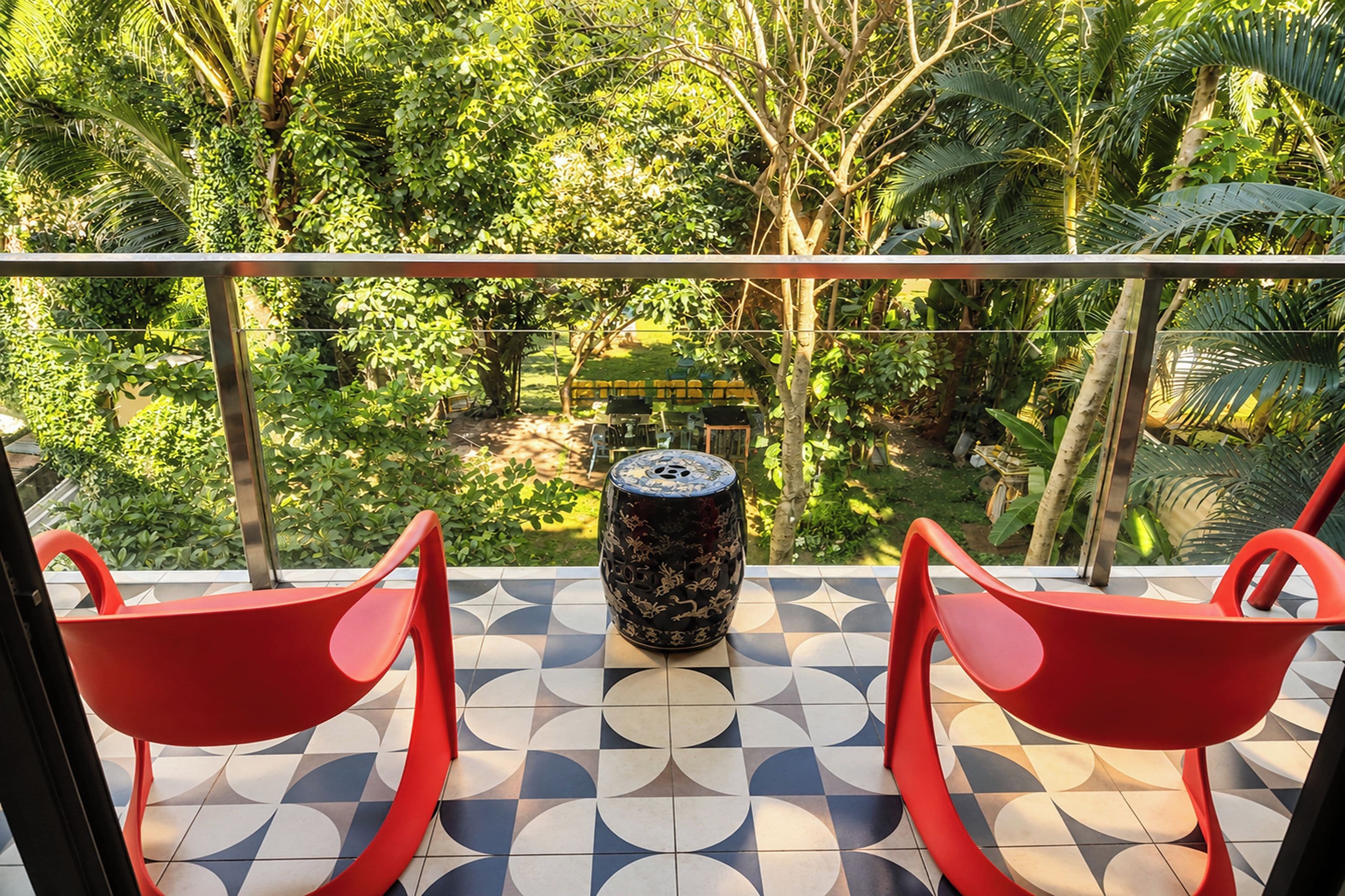 A balcony with two red chairs, a decorative vase, and a patterned floor.