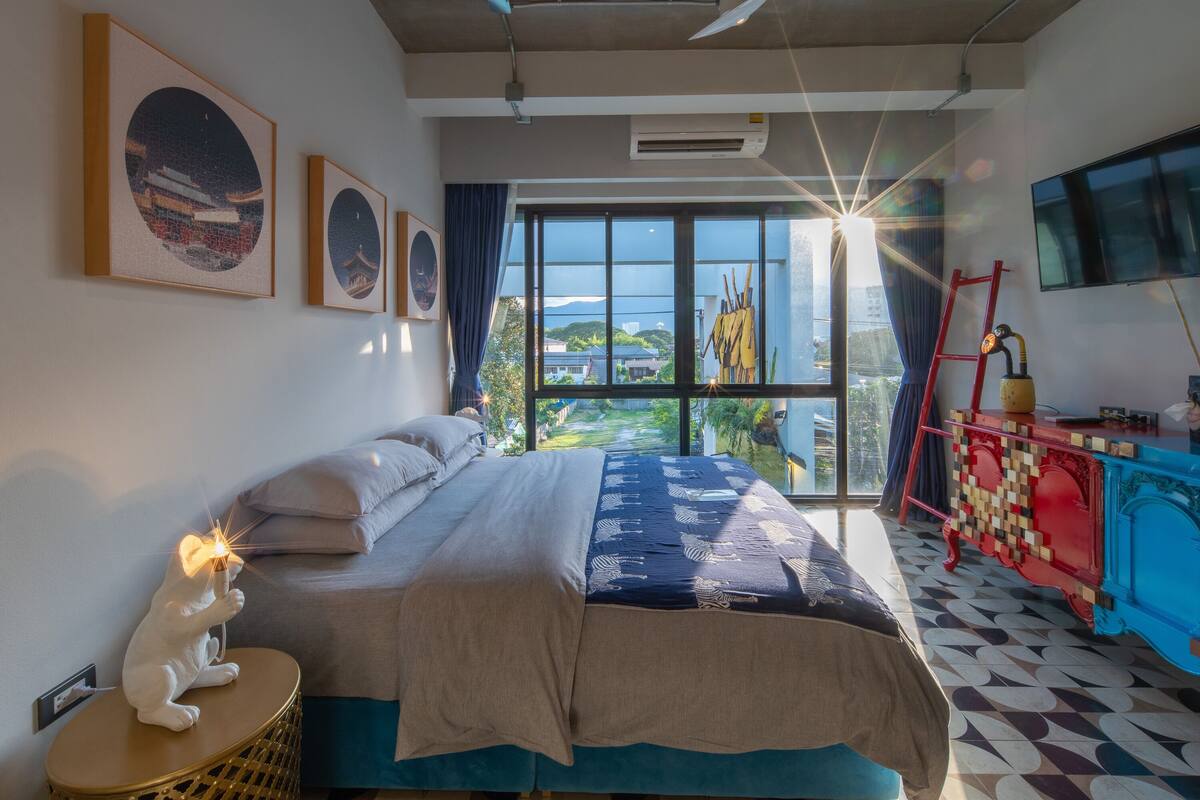 Une chambre avec un grand lit, une télévision et une vue sur l’extérieur.