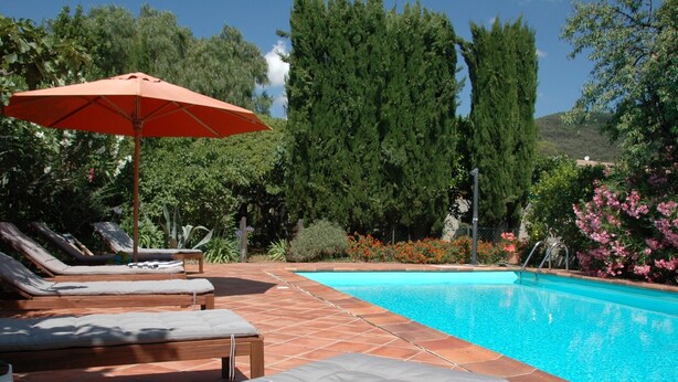 Une piscine avec des chaises longues et un parasol.