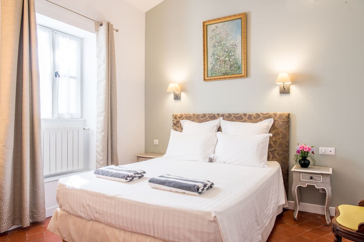 Une chambre d ’hôtel avec un grand lit, deux lampes de chevet, un tableau au mur et une petite table sur laquelle est posé un vase de fleurs.