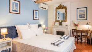 Une chambre d’hôtel équipée d’un lit, d’un bureau, d’une chaise, d’une cheminée et de tableaux encadrés aux murs.